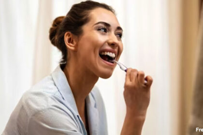 alt="A woman brushing her teeth in morning"