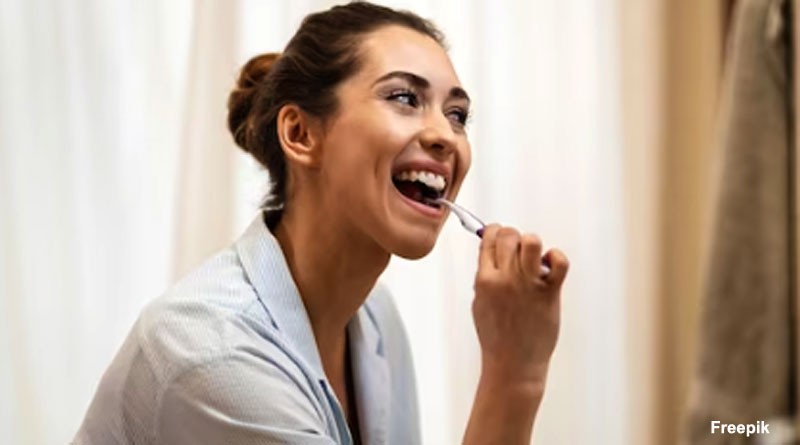 alt="A woman brushing her teeth in morning"