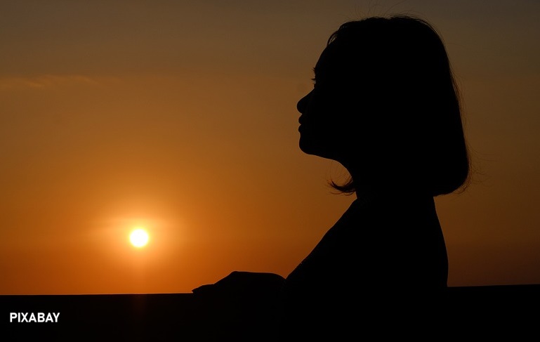 alt="woman hopefully looking at sunset"